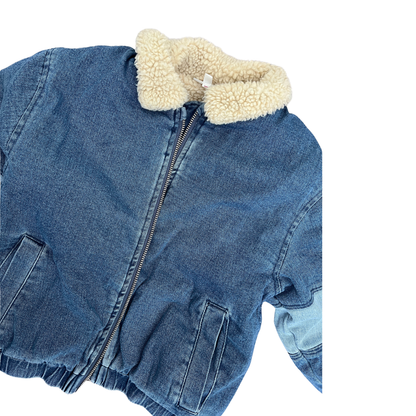 A cropped blue denim jacket with a cream-colored sherpa fleece collar, shown on a plain white background.